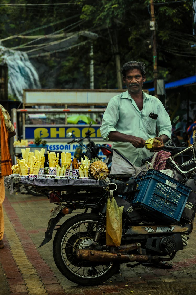 A Street Vendor Slicing A Pineapple