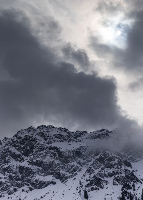 Free A dramatic view of a snow-capped mountain partially obscured by a cloudy sky, suggesting winter's chill. Stock Photo