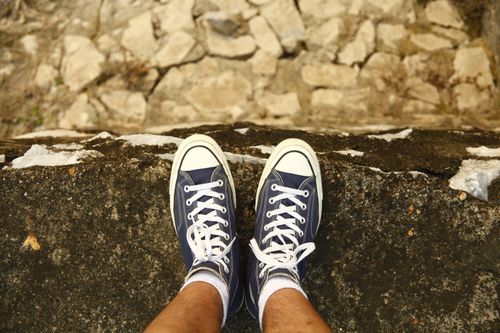 Free Pair of blue sneakers with white laces on a stone ledge, offering a unique perspective. Stock Photo