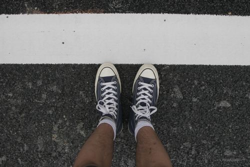 Free Top view of sneakers on asphalt road with a white line for an urban lifestyle vibe. Stock Photo