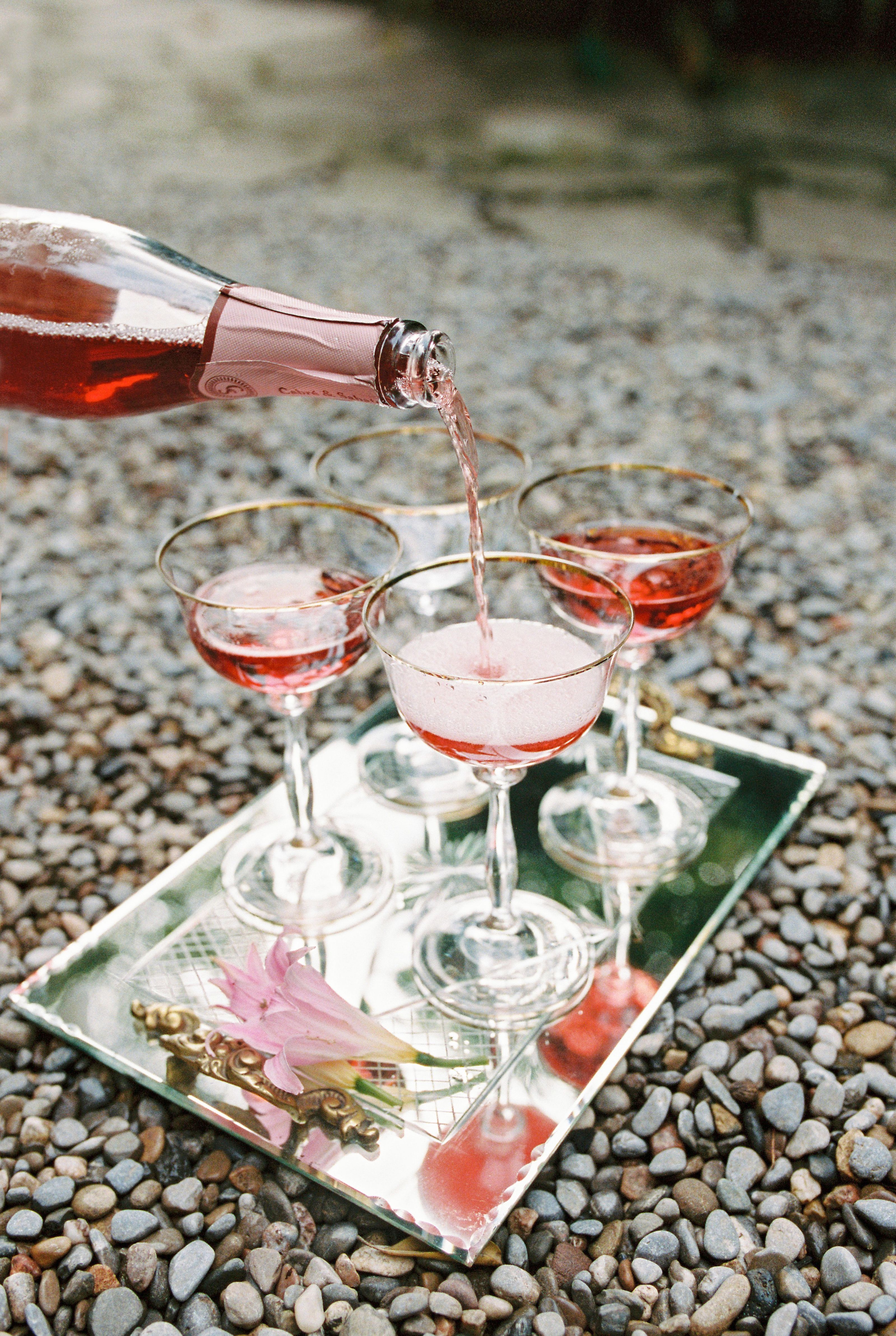 A sophisticated outdoor setting with wine being poured into elegant glasses on a reflective tray.