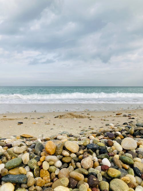 Rocky Shore Near Sea under White Clouds