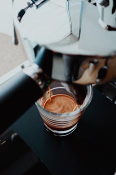 Close-up shot of espresso being brewed from a coffee machine into a glass cup.