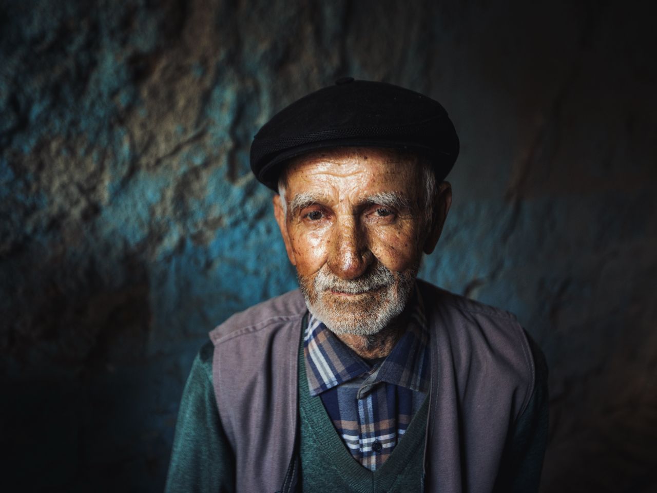 elderly man with facial hair and black flat cap gazing confidently