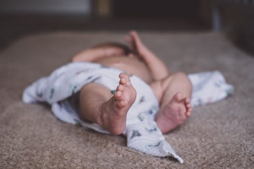 Baby Lying on Brown Surface