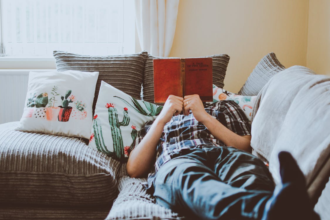Free Person Laying on Sofa While Reading Book Stock Photo