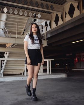 A young woman with long hair and urban fashion style walking indoors in Mexico City.