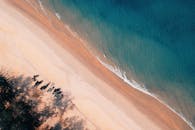 令人惊叹的空中拍摄捕捉到一片宁静的海滩，温柔的波浪，以及沙滩上的小船