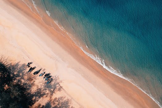 令人惊叹的空中拍摄捕捉到一片宁静的海滩，温柔的波浪，以及沙滩上的小船