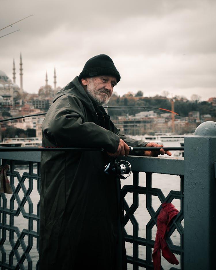 Fisherman In Coat On Bridge