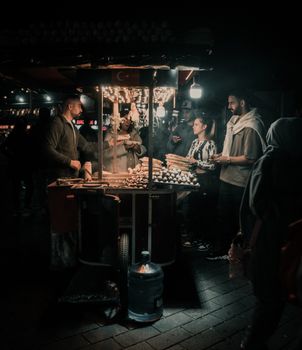 A bustling night scene at a food stand in Istanbul, Türkiye, capturing dynamic street life.