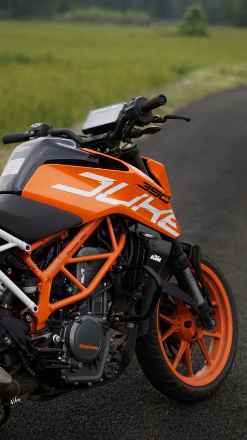 Free Close-up of an orange motorcycle parked on a rural road in New Delhi, India. Stock Photo