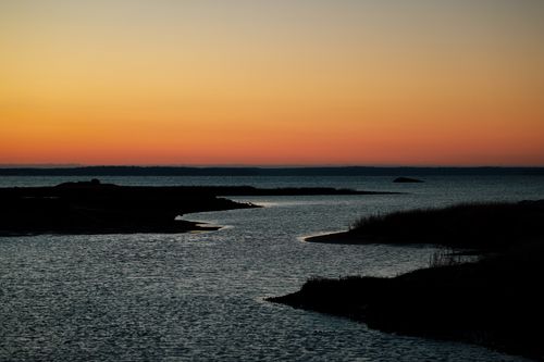 Free Tranquil sunrise over coastal waters with vibrant sky colors reflecting on the sea. Stock Photo