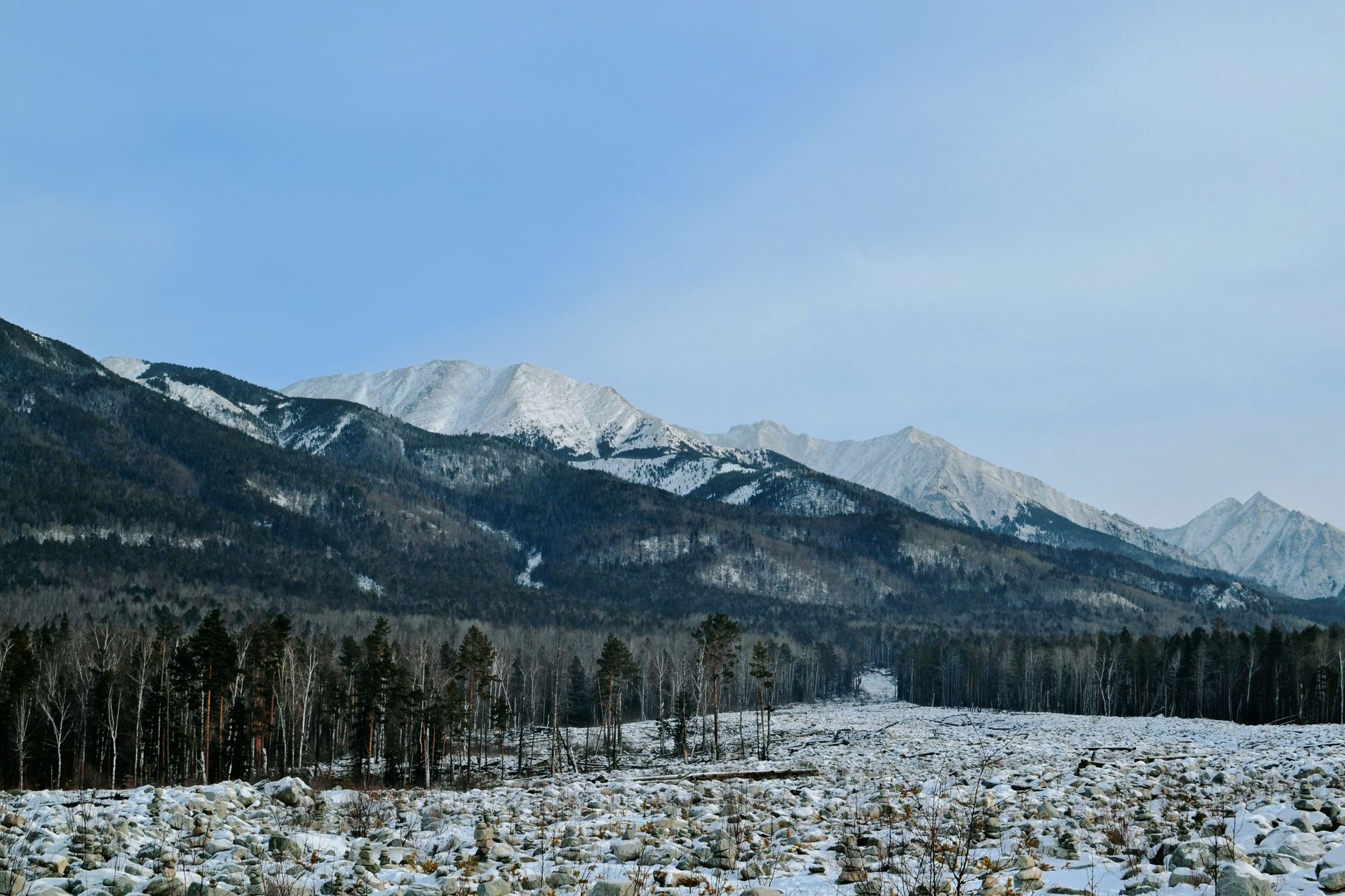 Scenic view of a snow-covered mountain range under a bright blue sky.