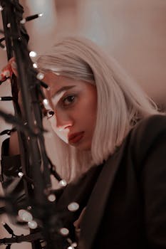 A captivating portrait of a young woman surrounded by twinkling string lights, evoking a thoughtful mood.