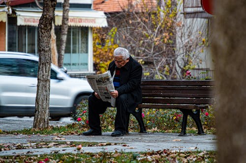 Elderly Man Sitting on a Bench and Reading a Restaurant 