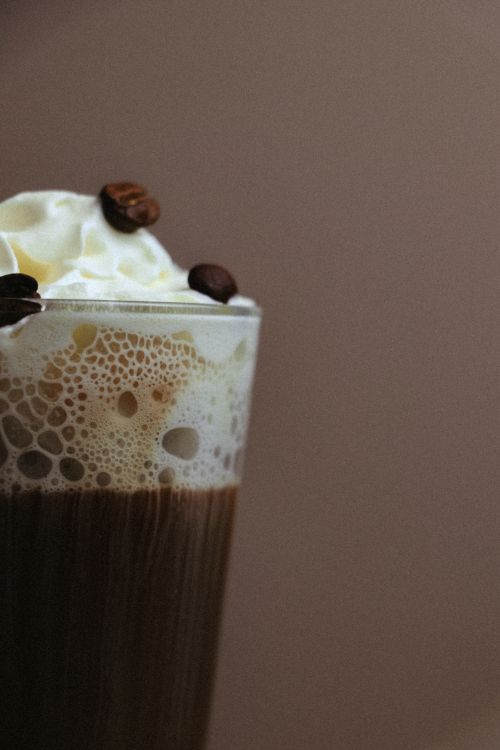 Free Close-up of frothy coffee with whipped cream and coffee beans. Stock Photo