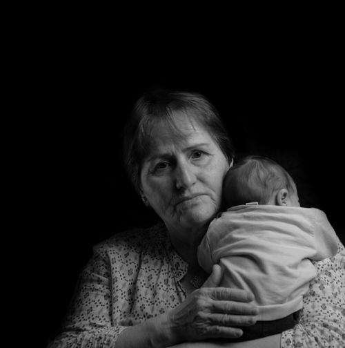 Free A heartfelt black and white portrait of an elderly woman holding a baby, symbolizing love and care. Stock Photo