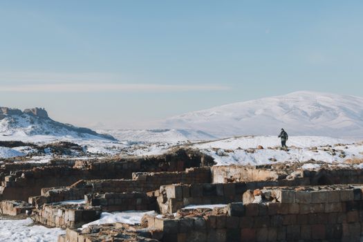 Snow-covered ancient ruins with distant mountains under a clear winter sky.