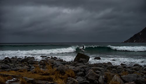 Person Surfing on Sea under Overcast Sky