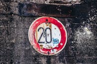 旧生锈限速标志上“20”字样的特写镜头，位于纹理混凝土墙上