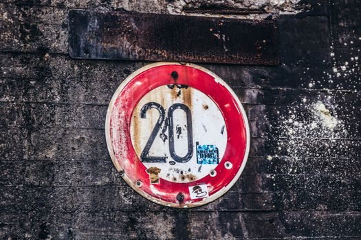 旧生锈限速标志上“20”字样的特写镜头，位于纹理混凝土墙上