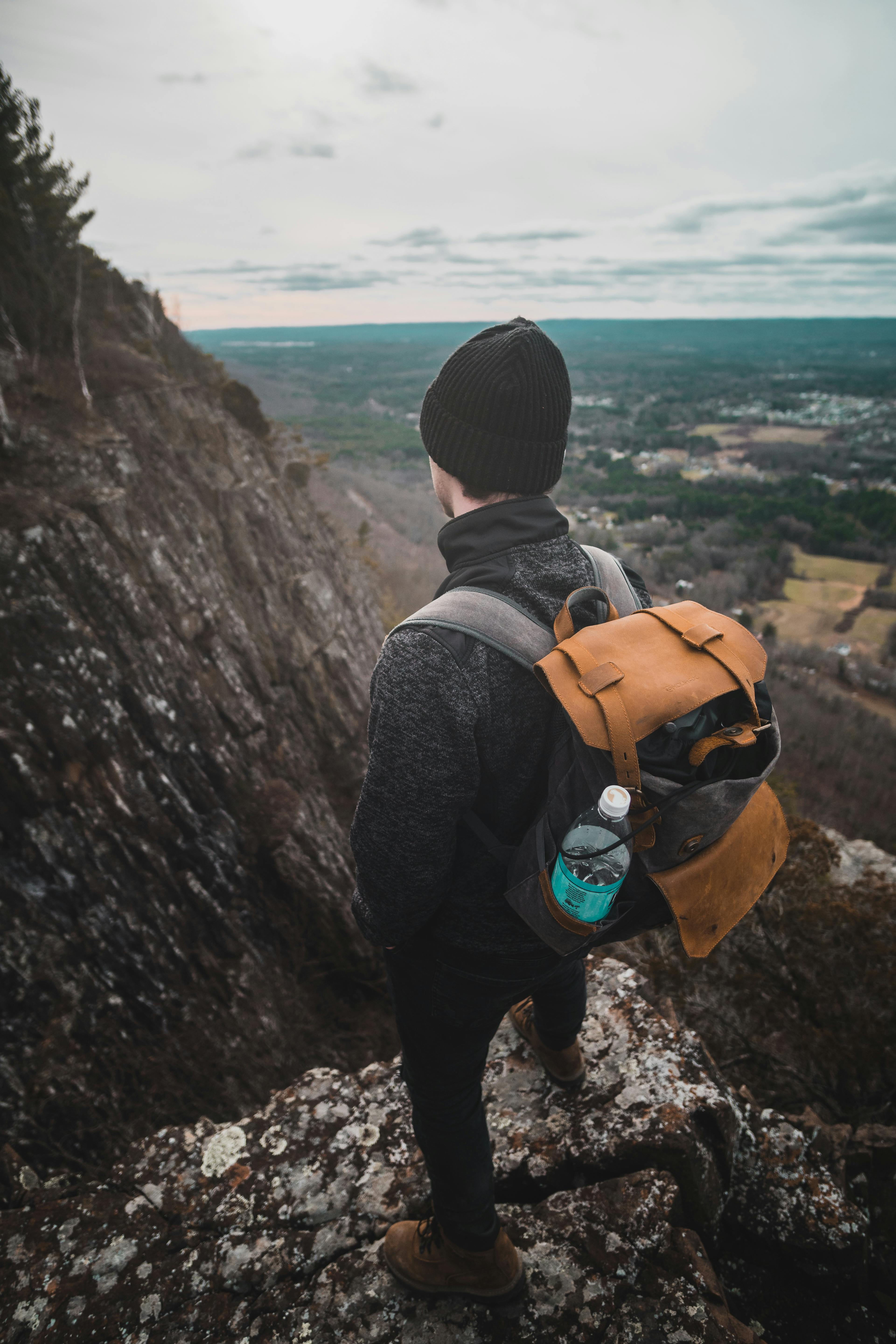 Photo of Man Standing on Cliff Edge Across Mountains · Free Stock Photo