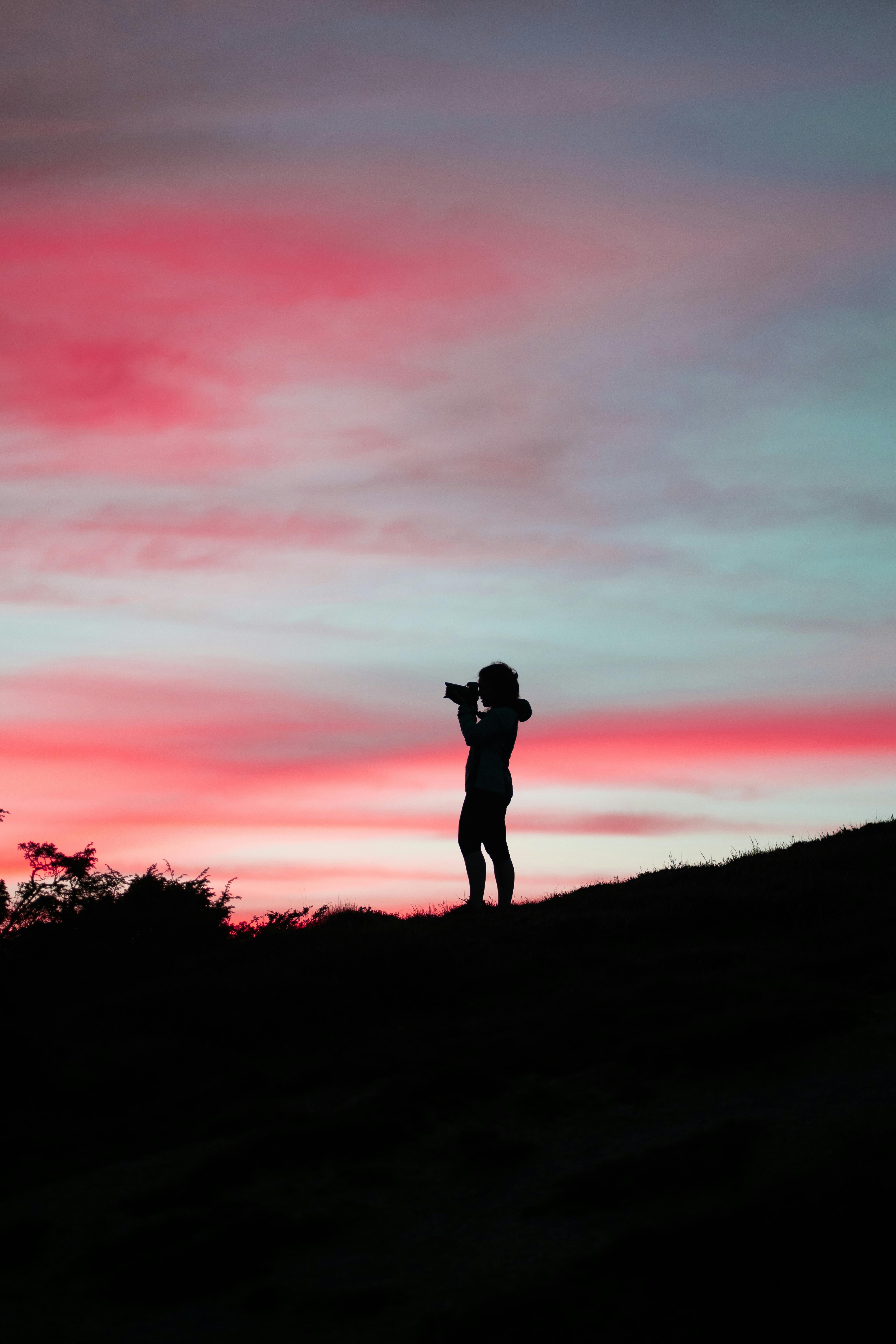 Photographer silhouette against a vivid sunset sky in Gavarnie, France.