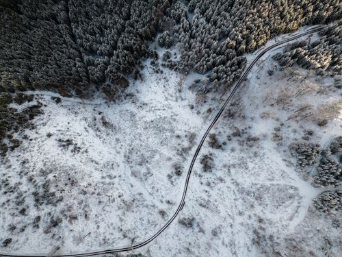 Free Aerial view of a snow-covered forest and road in Ilmenau, Germany. Stock Photo