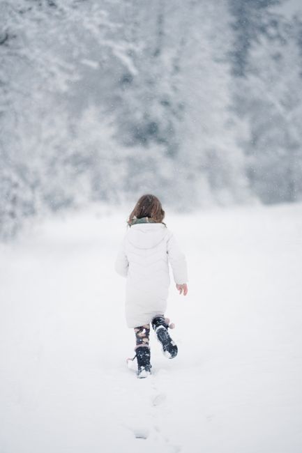 A young girl runs through a snowy forest, embracing the joys of winter.