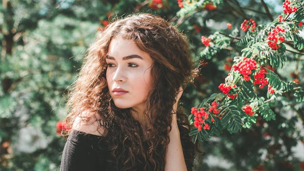 一位卷发年轻女子在户外摆放红果，散发着自然的美感