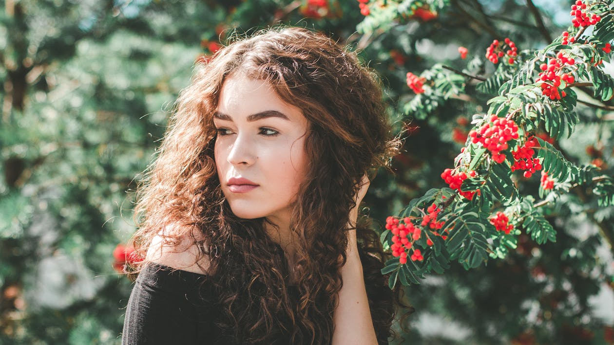 Woman Wearing Black Off Shoulder Shirt Standing Near Red Flower