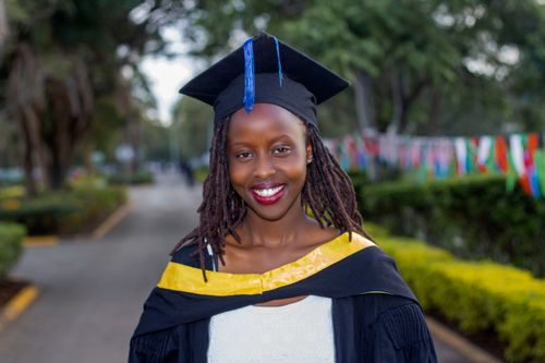 Free Joyful graduate wearing cap and gown at an outdoor ceremony. Stock Photo