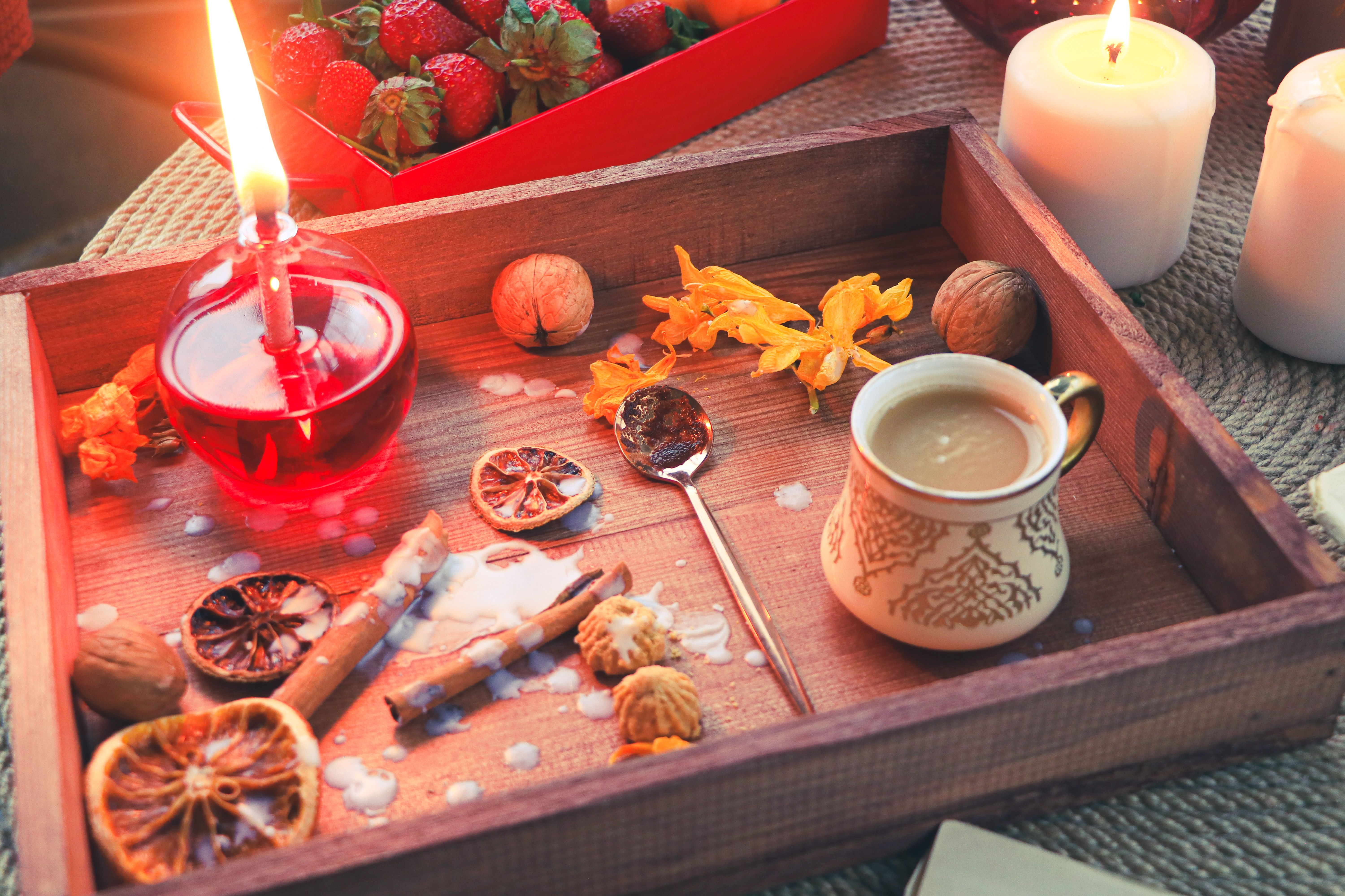 A warm mug of pinkish-gold liquid with cinnamon sprinkled on top, next to a candle