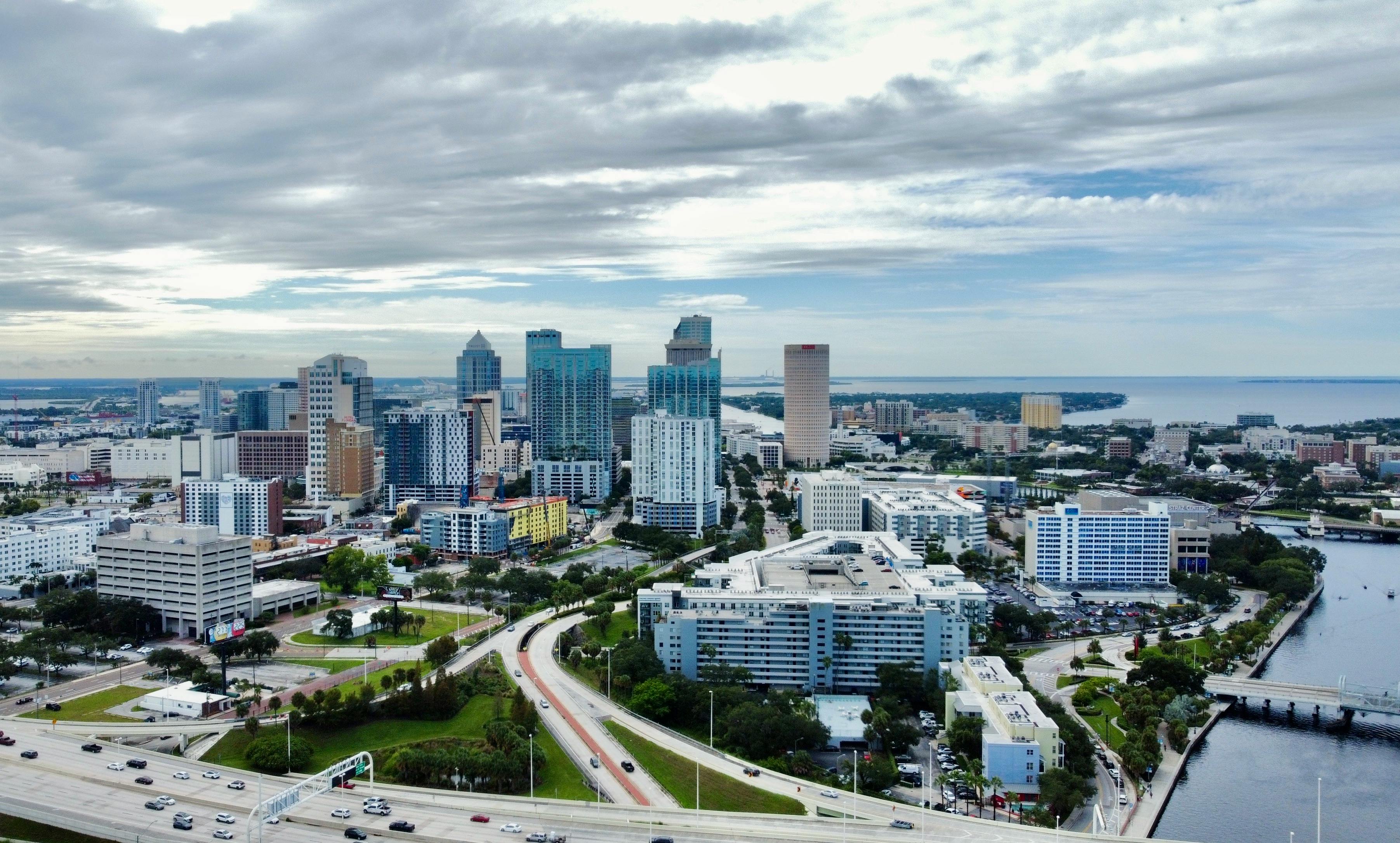 A stunning aerial view of Tampa, FL cityscape featuring modern skyscrapers against clouded skies.