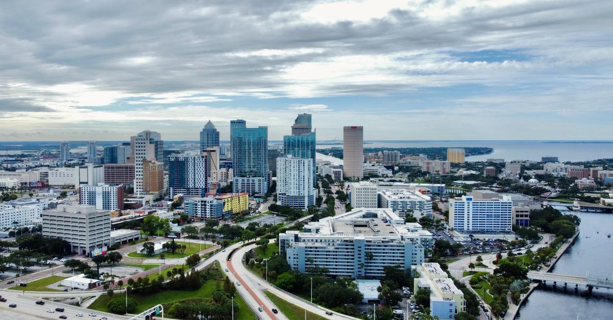 A stunning aerial view of Tampa, FL cityscape featuring modern skyscrapers against clouded skies.