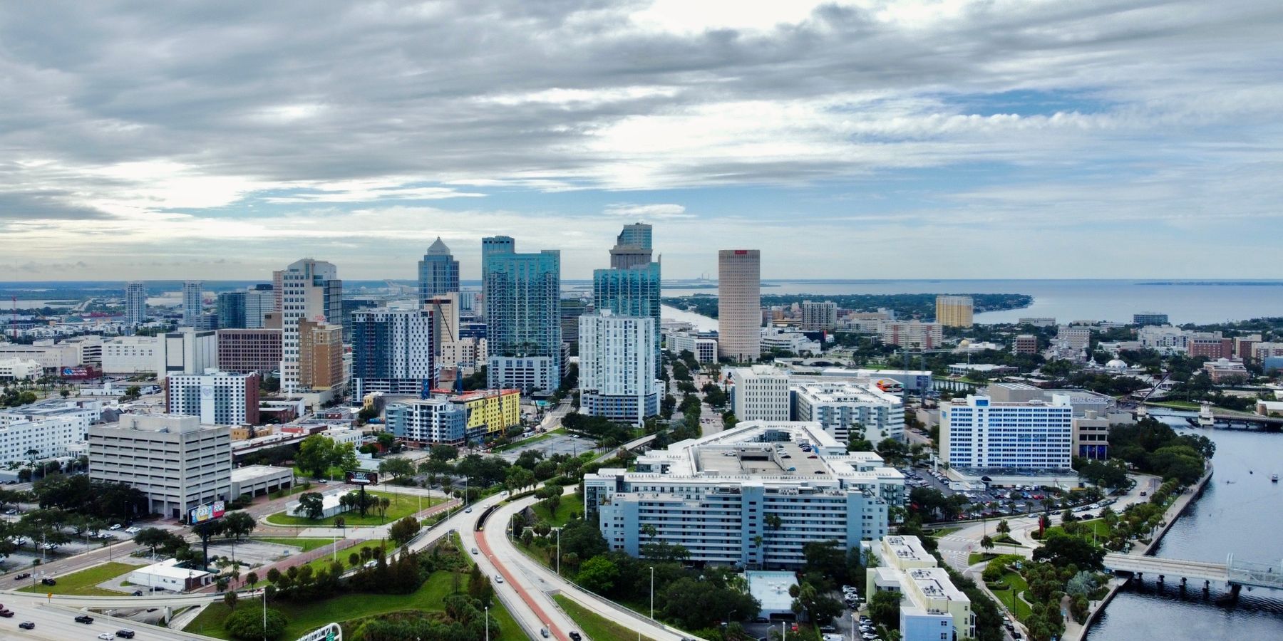 A stunning aerial view of Tampa, FL cityscape featuring modern skyscrapers against clouded skies.