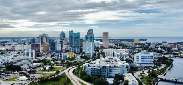 A stunning aerial view of Tampa, FL cityscape featuring modern skyscrapers against clouded skies.