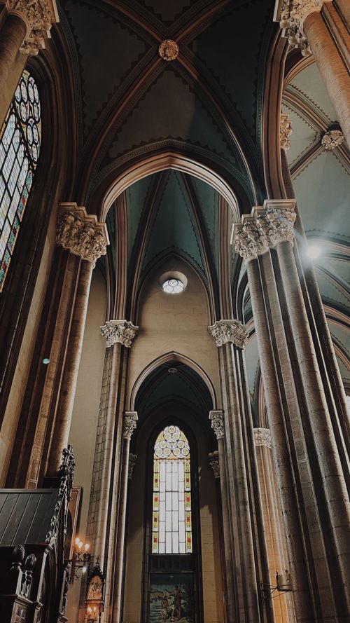 Free View of a grand cathedral interior featuring towering arches and stained glass windows. Stock Photo
