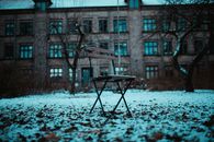 A solitary chair in a snow-dusted courtyard against an old building in Aalborg, Denmark.