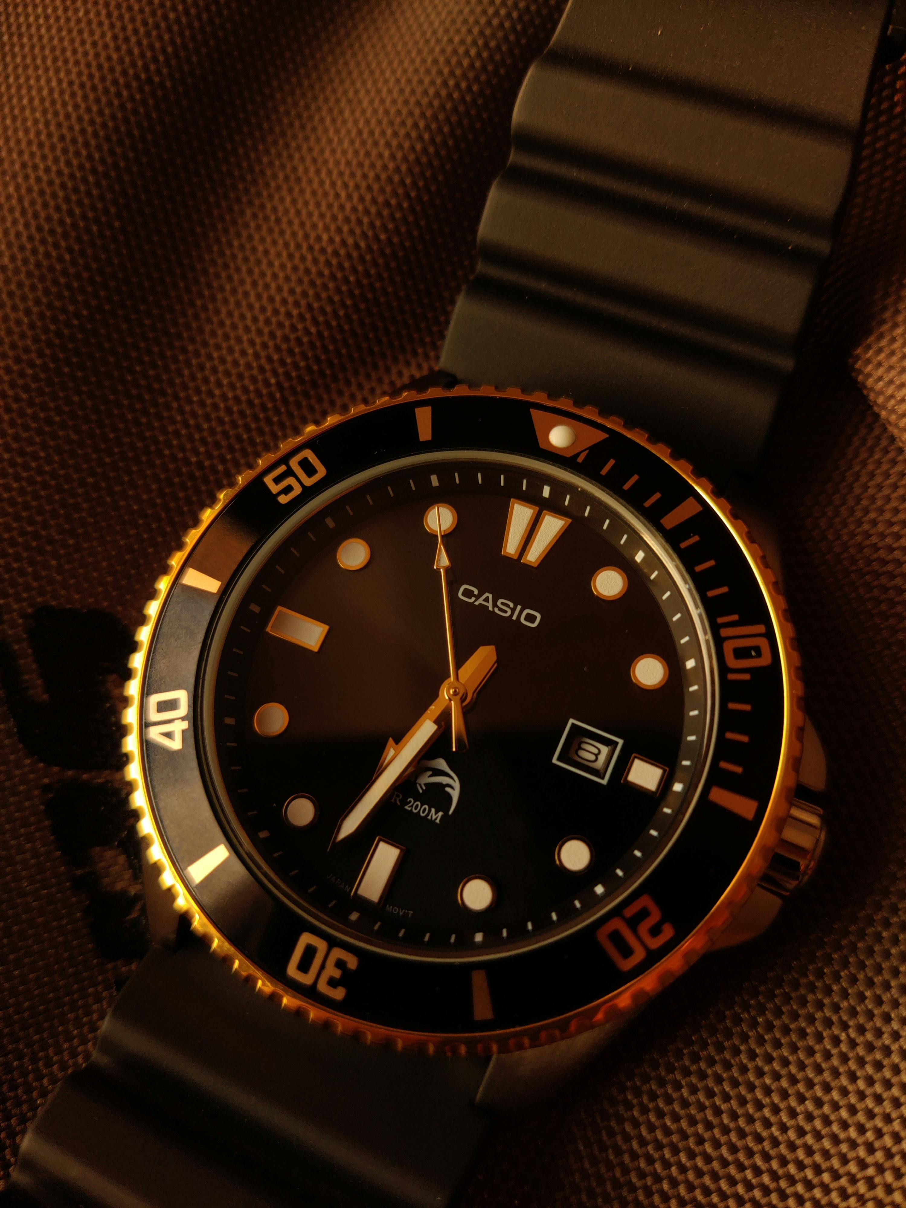 a black and gold watch on a brown background