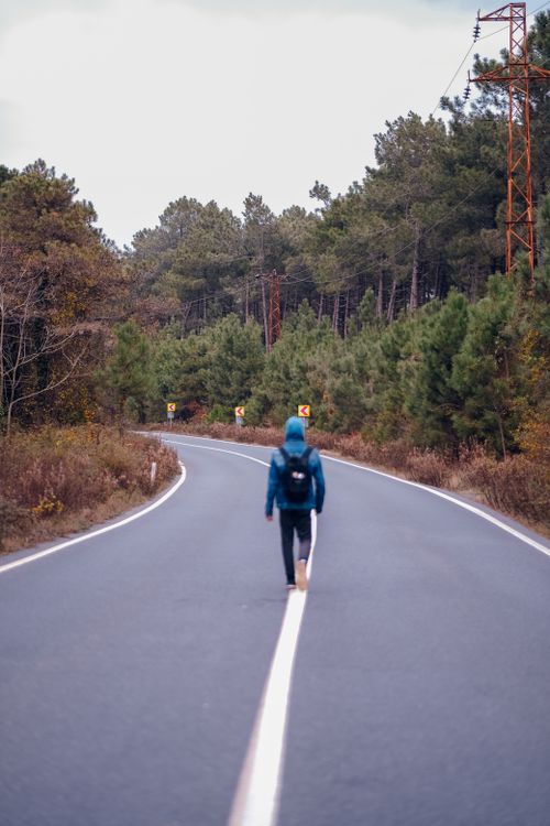 Free A person walking alone on a winding road through a forest, capturing solitude and peacefulness. Stock Photo