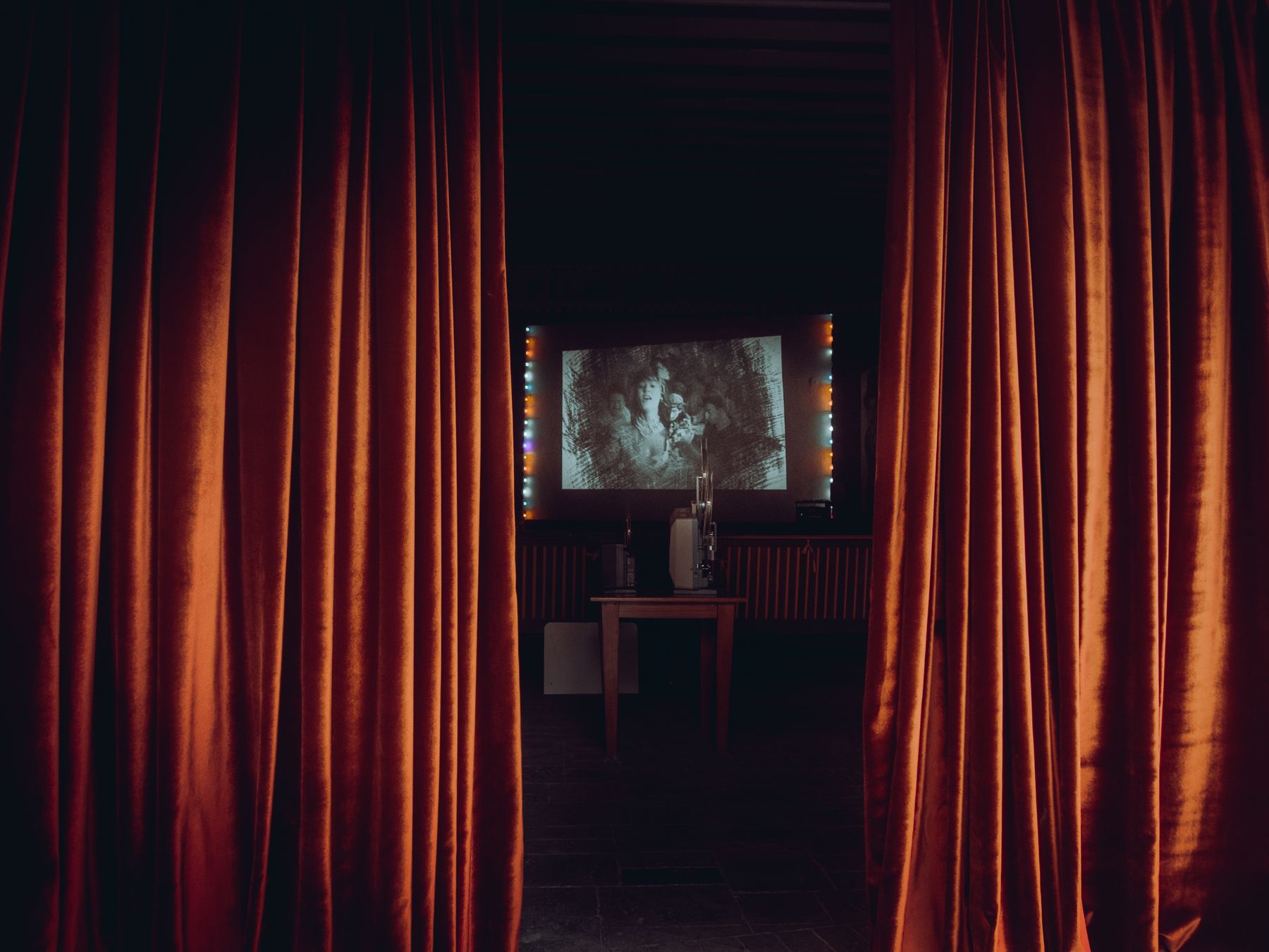 Looking through red cinema curtains into a screening room.