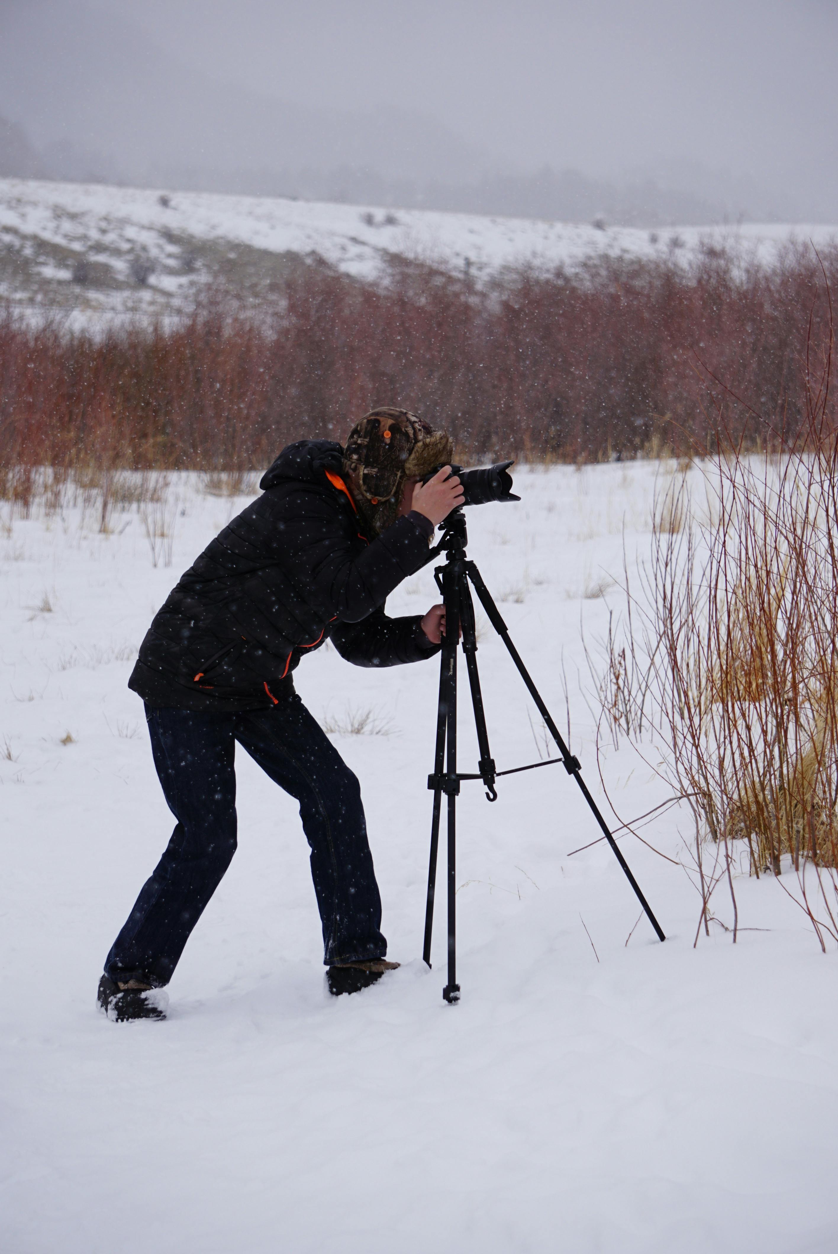 man taking photo in the middle of snow covered ground