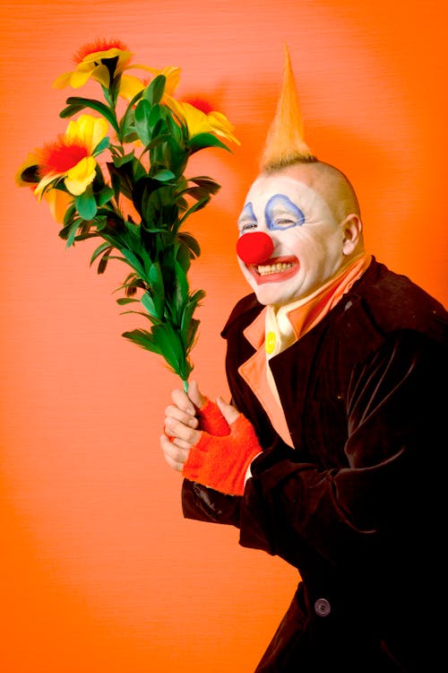 A Clown Holding an Artificial Flower 