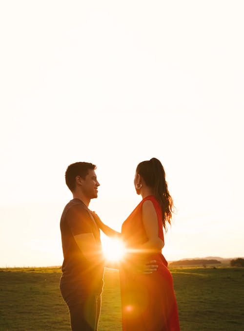 A Couple Standing on Grass Field during Sunset