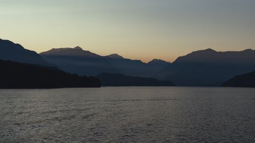 Free Tranquil sunrise over Vancouver's mountain range with calm waters, capturing dawn's serene beauty. Stock Photo