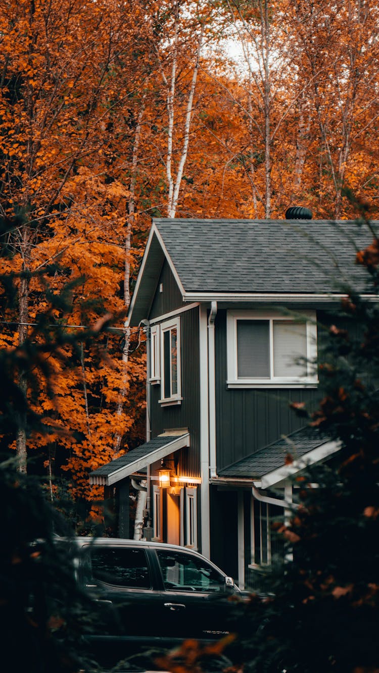 Car Parked In Front Of A House Among Autumnal Trees