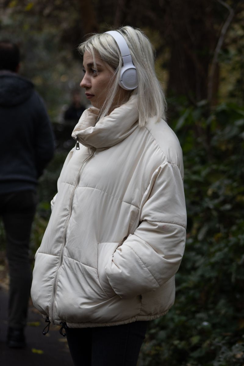 Blonde woman in a white puffer jacket wearing headphones