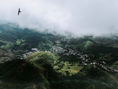 A stunning aerial view of Coronel Fabriciano with lush green hills and foggy skies.